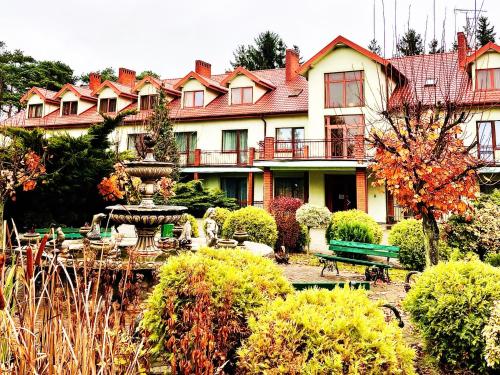 a large house with a fountain in a garden at Hotel Delicjusz in Trzebaw