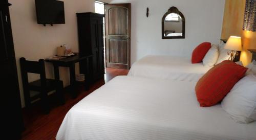 a hotel room with two beds and a television at Hotel Ciudad Vieja in Guatemala