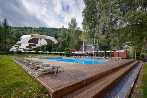 a pool with chairs and umbrellas on a wooden deck at Yaremche Club Hotel in Yaremche
