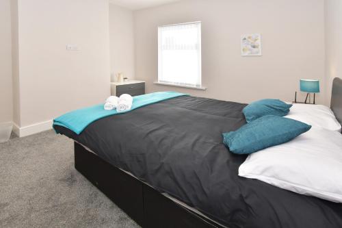 a bedroom with a large bed with blue and white pillows at Townhouse @ Warrington Road Stoke in Etruria