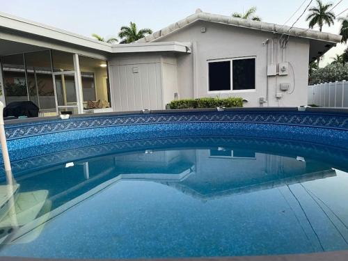 una piscina azul frente a una casa en SuperVilla - 3BR/2BA - Pool - Walk to beach, en Hollywood