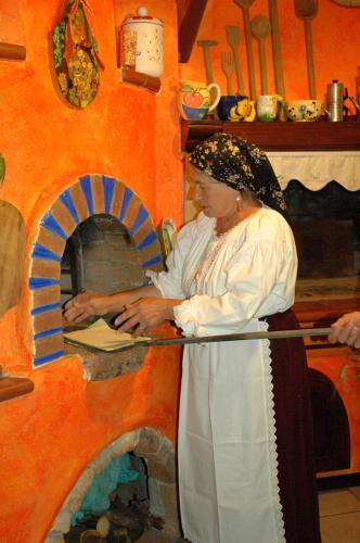 a woman standing in front of a pizza oven at B&B Rita and Family in Loceri