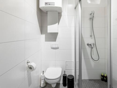 a white bathroom with a shower and a toilet at Limehome Villach Kirchenplatz in Villach