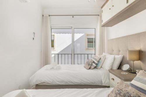 a white bedroom with a bed and a window at Typical Fisherman's Cottage with amazing sea views! in Albufeira