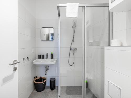 a white bathroom with a shower and a sink at Limehome Villach Kirchenplatz in Villach