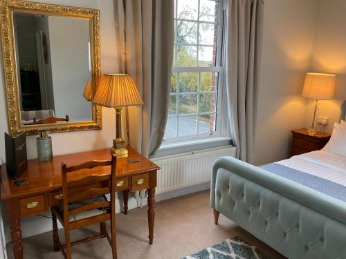 a bedroom with a desk and a bed and a mirror at The Broomsquire in Tadley