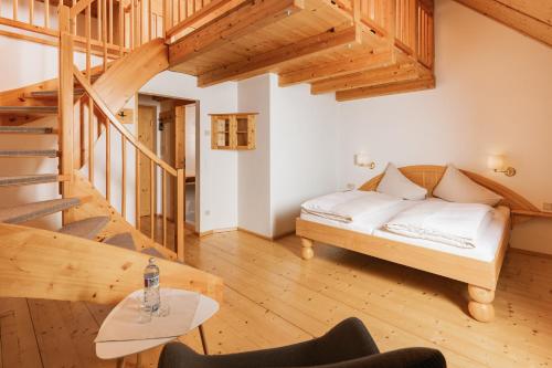 a bedroom with a bed and a wooden staircase at Naturhotel Landhof Irschen in Irschen