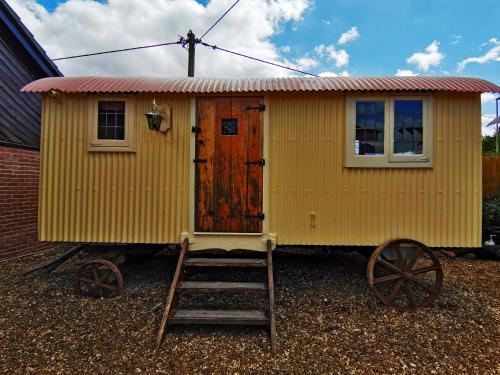 uma pequena casa sobre rodas com uma escada e uma porta em Stonehenge Inn & Shepherd's Huts em Amesbury