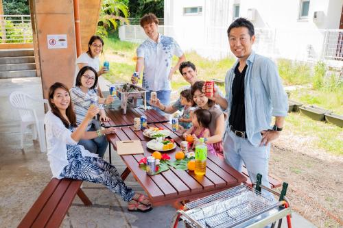 a group of people standing around a picnic table at ペンション ラナカイハウス沖縄 in Onna
