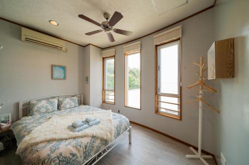 1 dormitorio con 1 cama y ventilador de techo en ペンション ラナカイハウス沖縄, en Onna