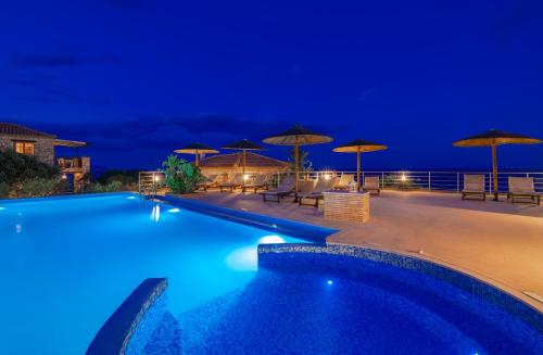 a swimming pool at night with umbrellas at Strofilia Authentic Villas in Skinária