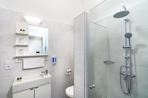 a bathroom with a shower and a toilet and a sink at RES City Residence Hotel Budapest in Budapest