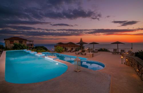 a swimming pool with a sunset in the background at Strofilia Authentic Villas in Skinária