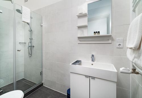 a white bathroom with a sink and a shower at RES City Residence Hotel Budapest in Budapest