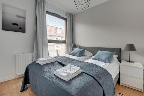 a bedroom with a bed with blue pillows and a window at Opal K2009 Grand - Tourist Apartments in Gdańsk