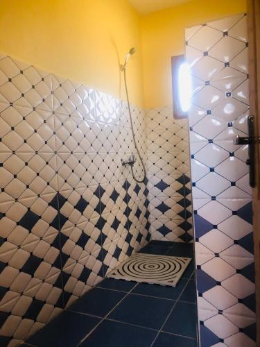 a bathroom with a shower with a tiled wall at Riad Hotel Les Flamants in Merzouga