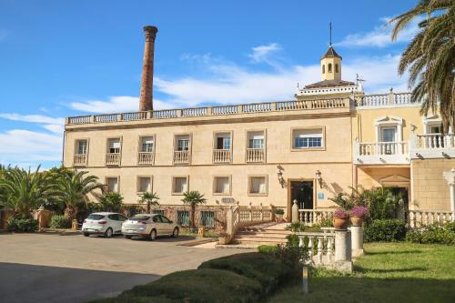 a large building with cars parked in front of it at Hotel Las Navas in Malagón