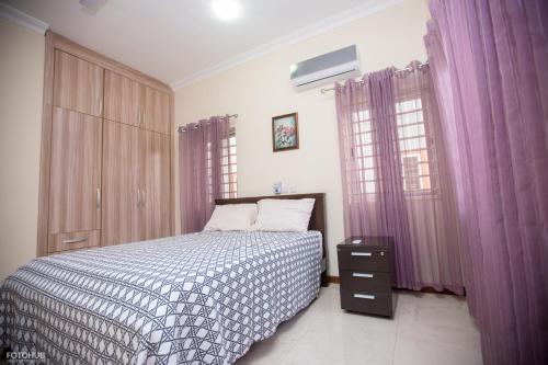 a bedroom with a bed and purple curtains at Aviation Highway Apartment in Spintex