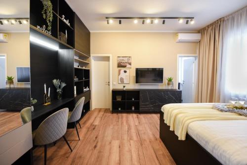 a bedroom with a bed and two chairs and a television at MONOCHROME MAGIC. Calea Victoriei Studio in Bucharest