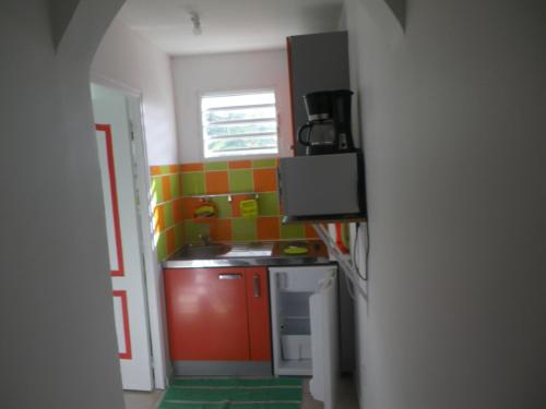 una pequeña cocina con paredes de color naranja y verde. en IMMEUBLE NEBOT en Grand-Bourg