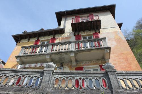 a tall building with red windows and a balcony at B&B Il Balcone sul Lago in Brunate