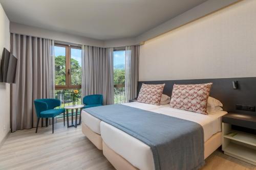 um quarto de hotel com uma cama e uma varanda em Enotel Magnólia no Funchal