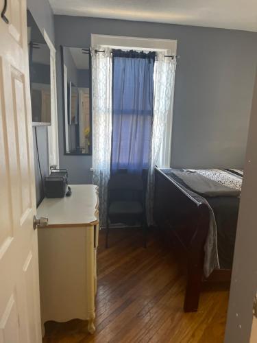 a bedroom with a bed and a window with a chair at Royalbluecozy in Saint Albans