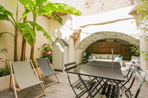 un patio avec une table, des chaises et un canapé dans l'établissement La Maison Rose, à Grignan