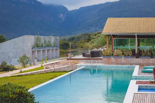 a swimming pool with a house and mountains in the background at Pousada Amanhecer in Vale do Capao