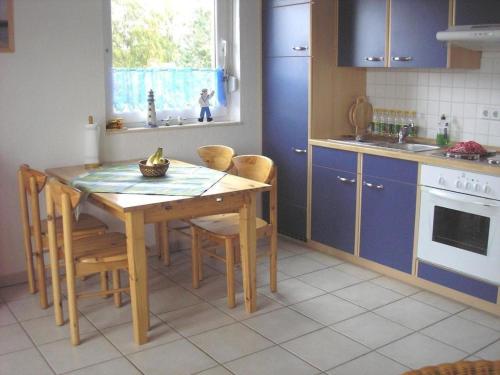a kitchen with a wooden table and blue cabinets at Ferienwohnung Möwe - a09392 in Zingst