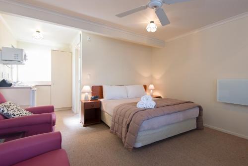 a bedroom with a bed and a couch and a tv at Hamilton Settlers Motor lodge in Hamilton