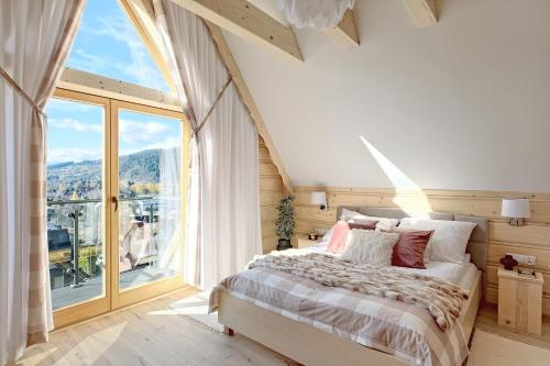 a bedroom with a bed and a large window at Osada Bachledzki Wierch Odkryj Zakopane in Zakopane