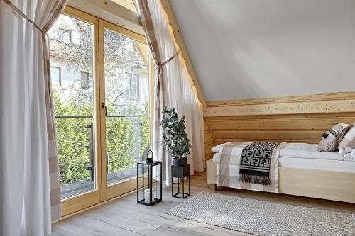 a bedroom with a bed and a large window at Osada Bachledzki Wierch Odkryj Zakopane in Zakopane