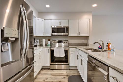 a kitchen with white cabinets and a stainless steel refrigerator at Orange Beach Condo with Shared Pool and Views! in Orange Beach
