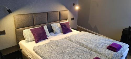 a bedroom with a bed with purple and white pillows at Pension Schmatka Matka in Lutherstadt Eisleben