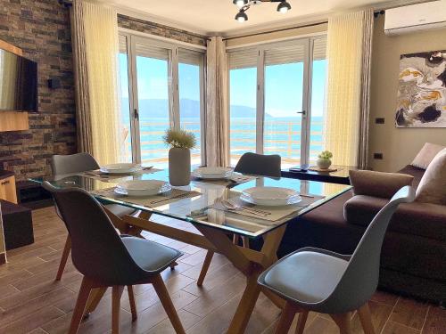 sala de estar con mesa, sillas y sofá en Eka Luxury Beachfront One-Bedroom Apartment, en Vlorë