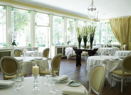 a restaurant with white tables and chairs and windows at Hotel Frederiksminde in Præstø