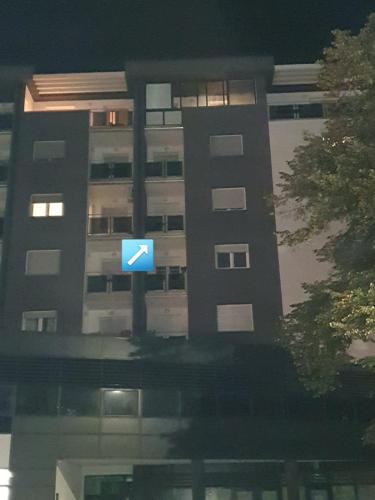 a blue sign in front of a tall building at Apartman Basic 2 in Doboj