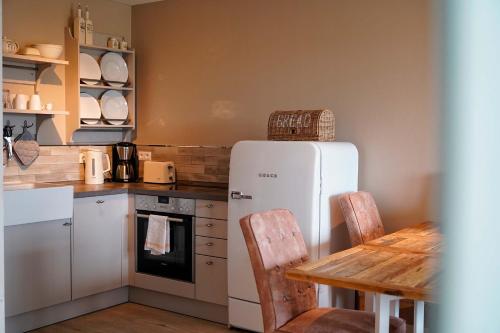 a kitchen with a white refrigerator and a wooden table at Beach Apartments Heiligenhafen in Heiligenhafen