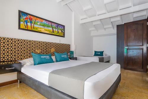 a bedroom with a large white bed with blue pillows at Ayenda La Tua Casa in Bogotá