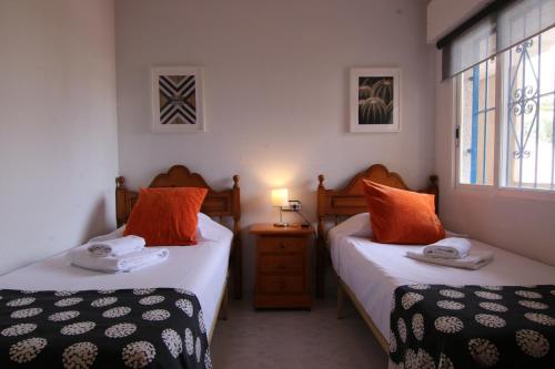 1 dormitorio con 2 camas con almohadas de color naranja en Altaia Apartment, en Altea