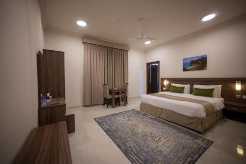 Un dormitorio con una cama grande y una mesa. en Anisa Residential Complex en Salalah