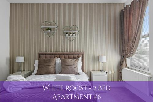 a bedroom with a white root bed with purple sheets at The Roost Group - Bedford House Apartments in Gravesend