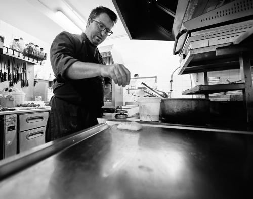 a man standing in a kitchen preparing food at Le Thalassa Hôtel & Spa in Camaret-sur-Mer
