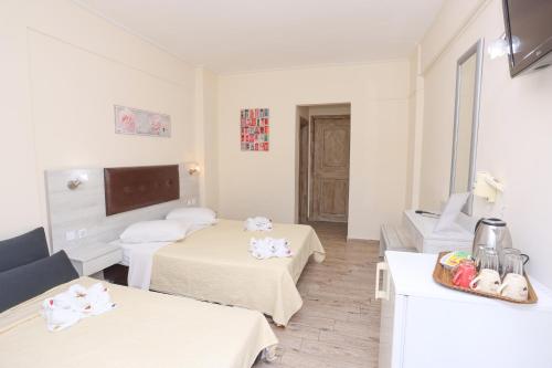 a white room with two beds and a mirror at Summer Beach Hotel in Polykhrono