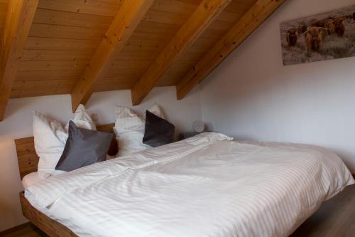 a bedroom with a bed with white sheets and pillows at Kuschelige Ferienwohnung mit Balkon & Free Wifi in Buchenberg
