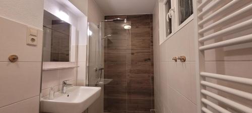 a white bathroom with a sink and a shower at Ermis Apartments in Metzingen