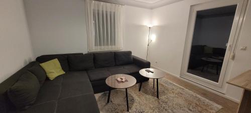 a living room with a black couch and two tables at Ermis Apartments in Metzingen