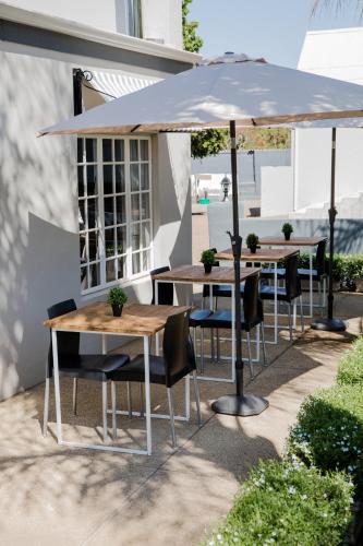 a group of tables and chairs under an umbrella at Elianthe Guesthouse in Swellendam