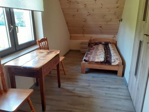 a room with a bed and a table and a bench at zajęcza chata in Dolistowo